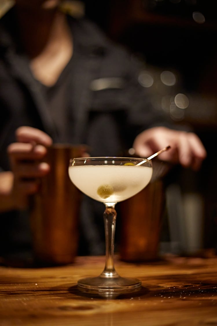 Barman making a martini cocktail at a bar