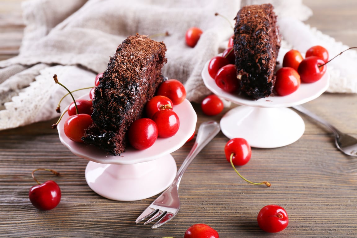 Chocolate Roll with Cherries in Saucer on Wooden Background