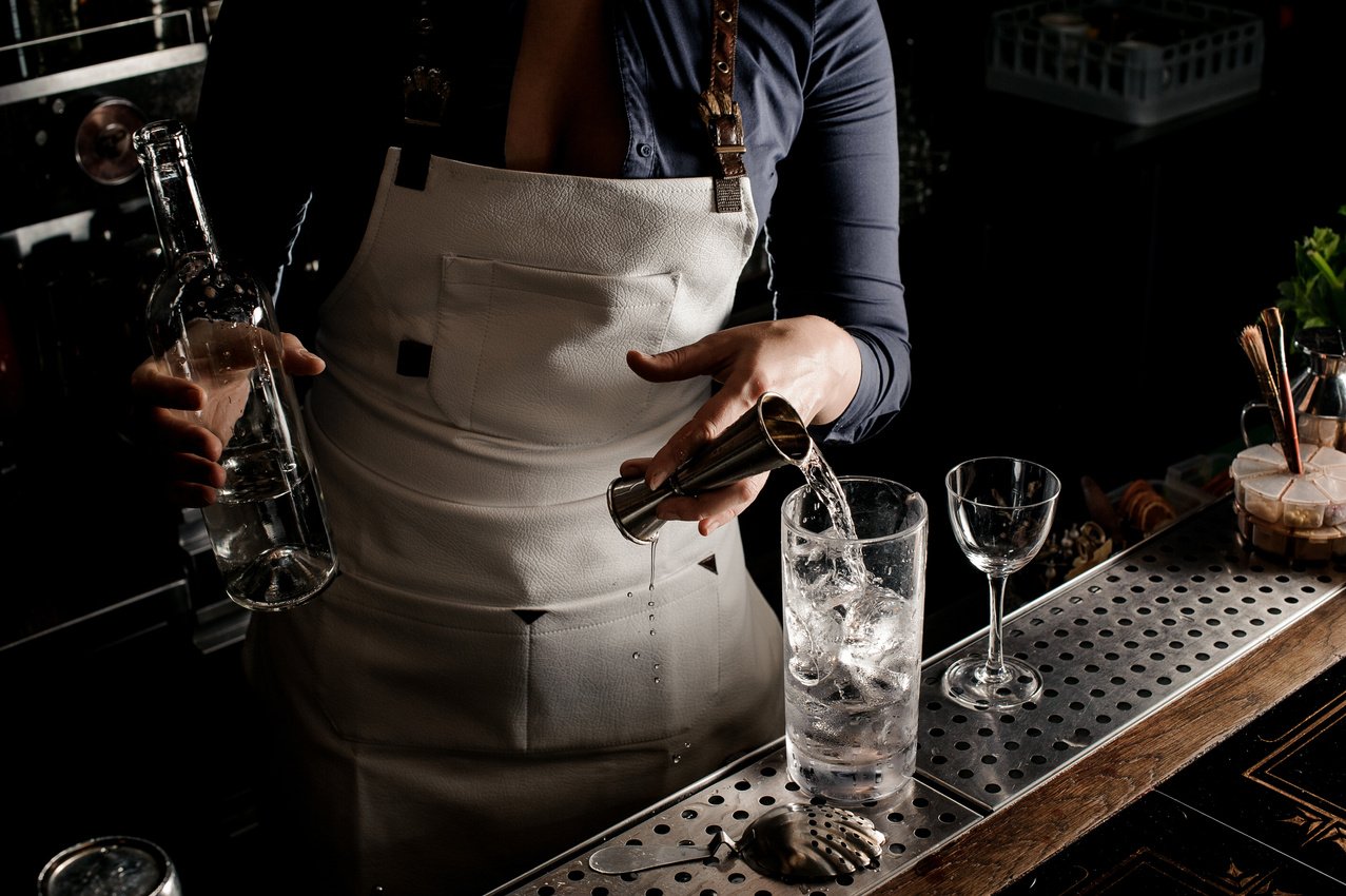 Hot barman woman pouring gin into a cocktail glass